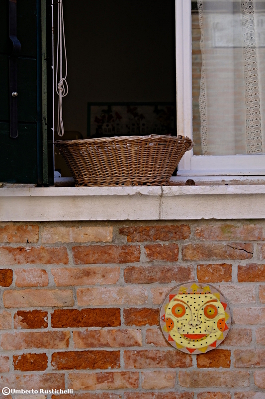 Venice, a sun made of wood decorates the red wall of a house